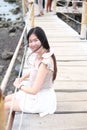 Happiness of asian woman is sitting on wooden bridge Extending into the sea on Holiday. She is smiling in the natural wind and sea Royalty Free Stock Photo